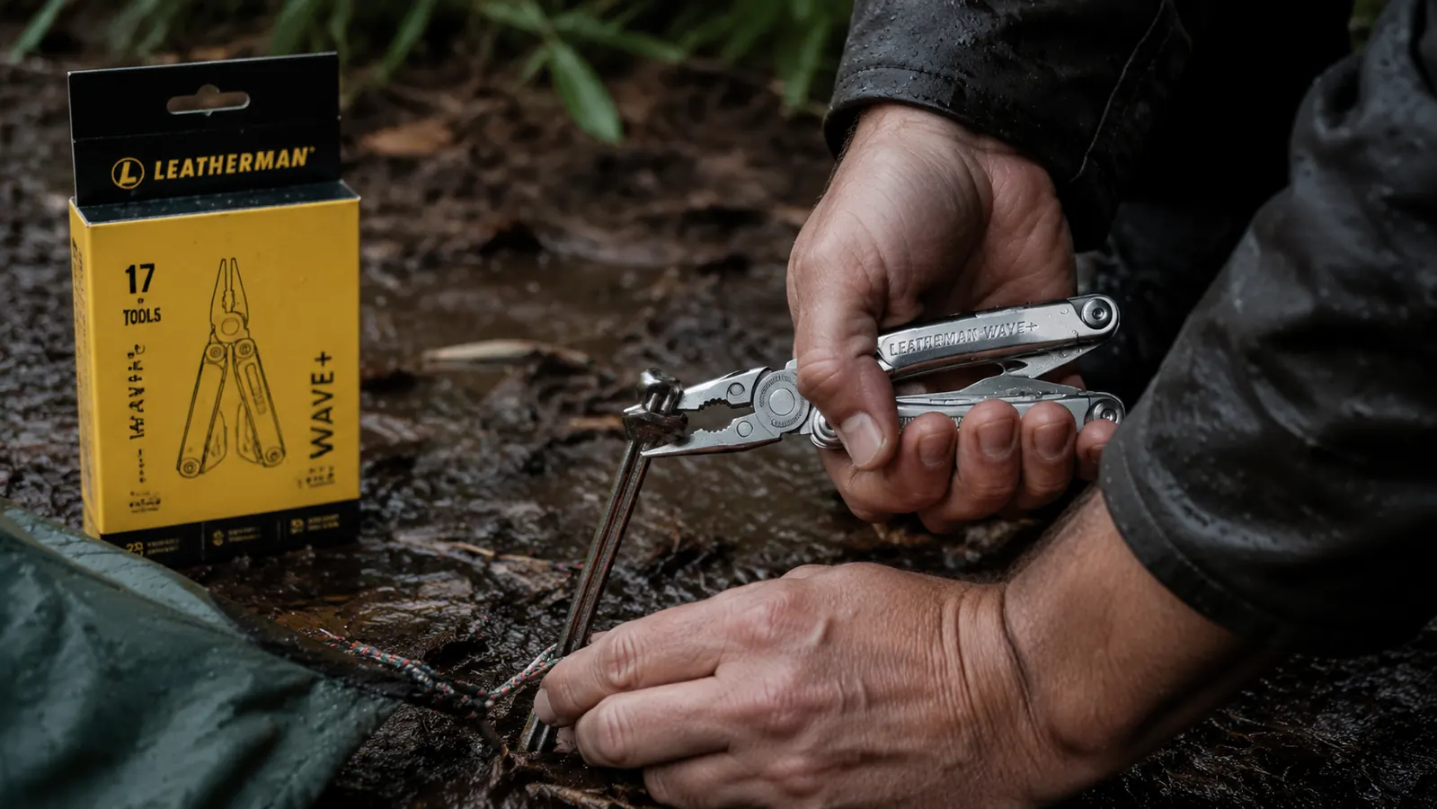 Hand opening the pliers on a Leatherman Wave+ while repairing a tent stake in a campsite