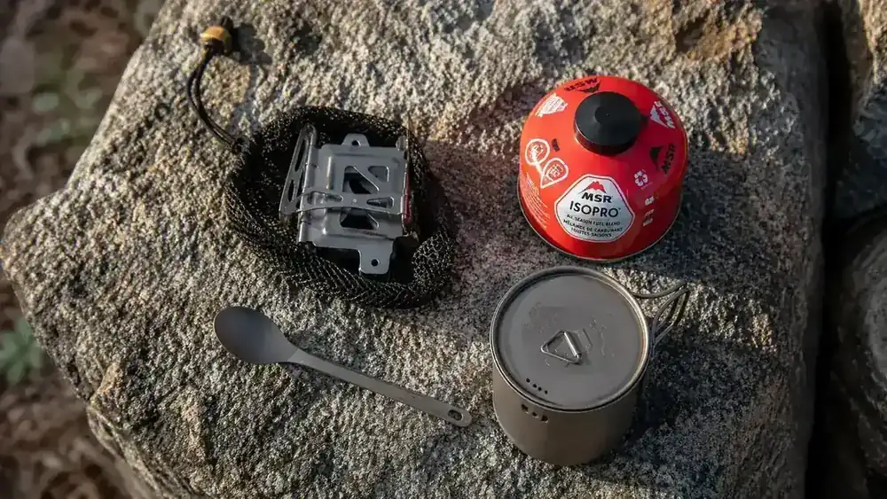 Pack contents laid flat showing the BRS-3000T stove in its case alongside a fuel canister and cook kit