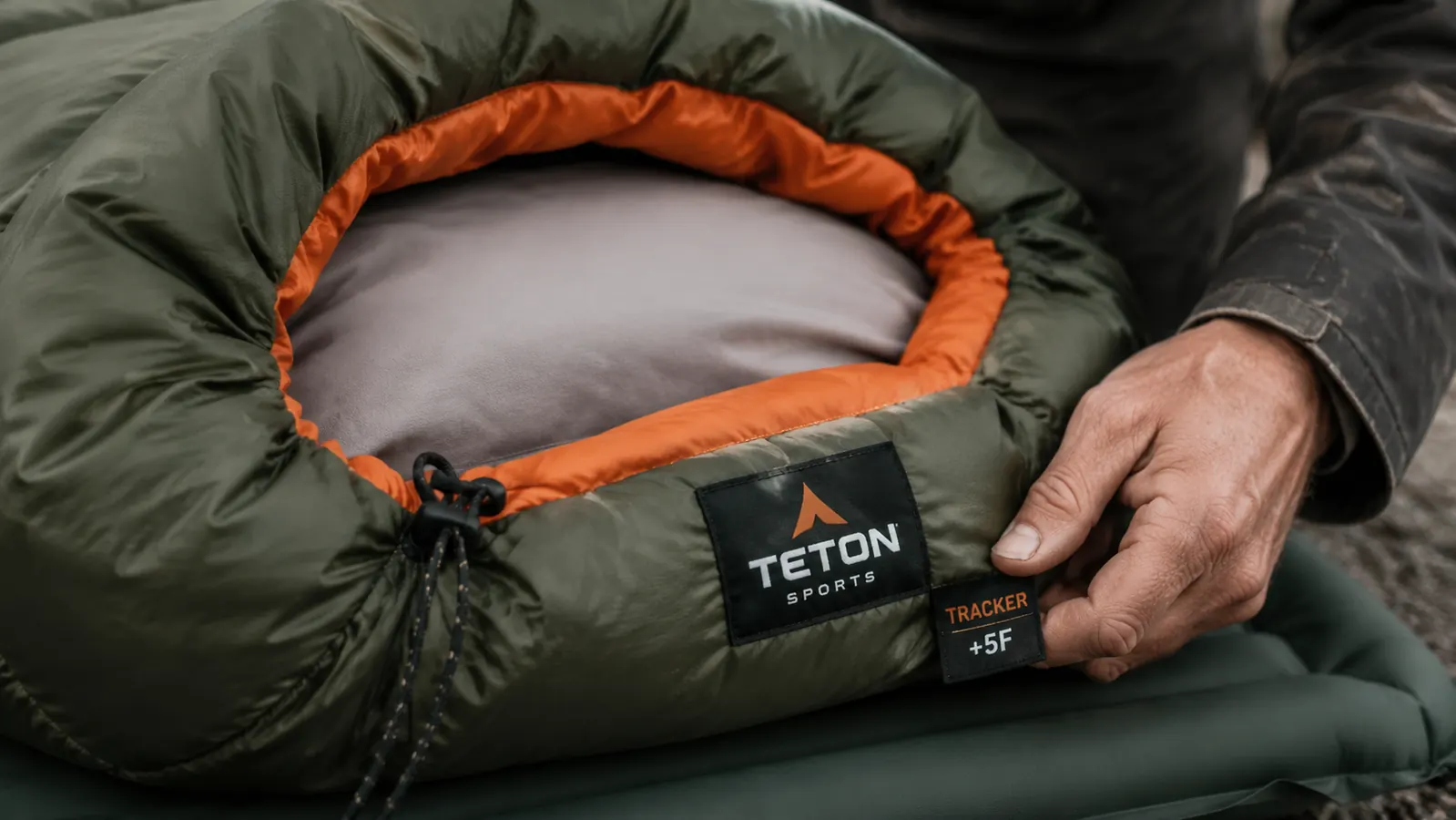 Close-up of a sleeping bag temperature rating label and zipper pull, warm interior lining visible